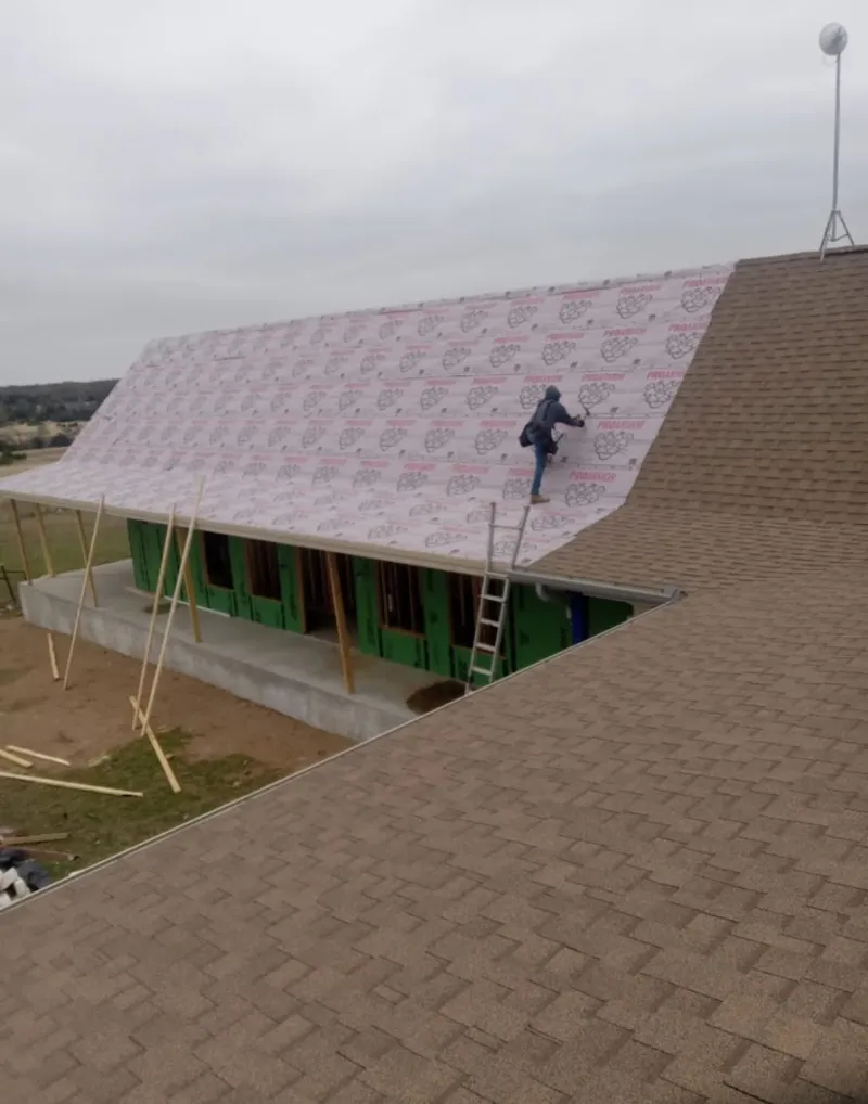 Worker preparing underlayment for a metal roof installation in Slaton